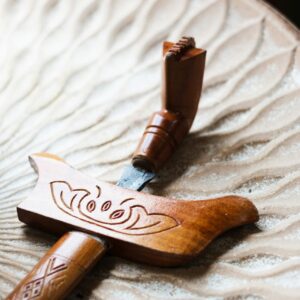 Close-up of a traditional Malay keris with wooden hilt and sheath on a textured background.