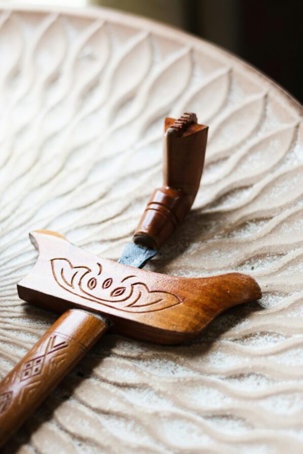 Close-up of a traditional Malay keris with wooden hilt and sheath on a textured background.